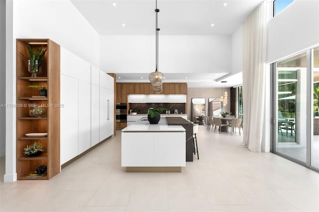 kitchen featuring pendant lighting, backsplash, white cabinets, plenty of natural light, and a center island