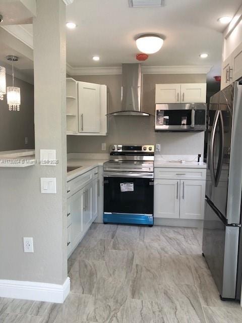 kitchen featuring crown molding, hanging light fixtures, white cabinetry, wall chimney range hood, and stainless steel appliances