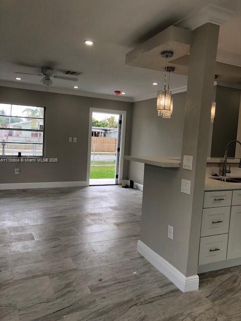 interior space featuring sink, ceiling fan, and crown molding