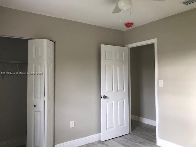 unfurnished bedroom featuring light hardwood / wood-style floors, a closet, and ceiling fan