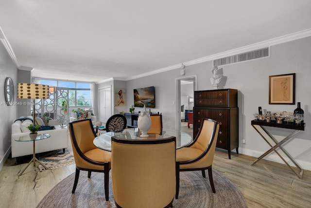 dining room with ornamental molding, light wood-type flooring, and a wall of windows