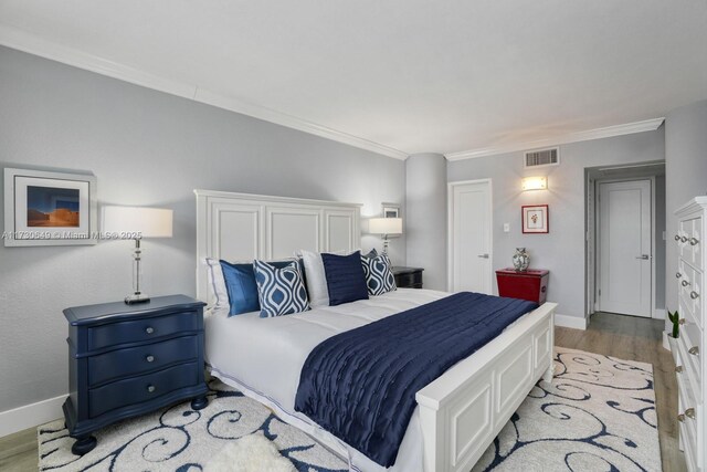 bedroom featuring crown molding and light hardwood / wood-style flooring