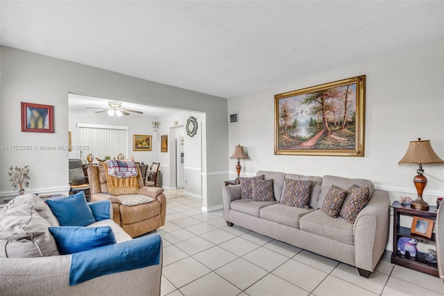 living room featuring ceiling fan, a textured ceiling, and light tile patterned floors