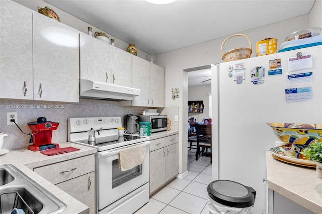 kitchen with decorative backsplash, white appliances, and light tile patterned floors