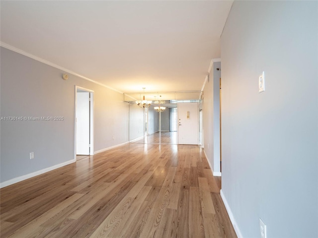 unfurnished room featuring light wood-type flooring, ornamental molding, and a notable chandelier