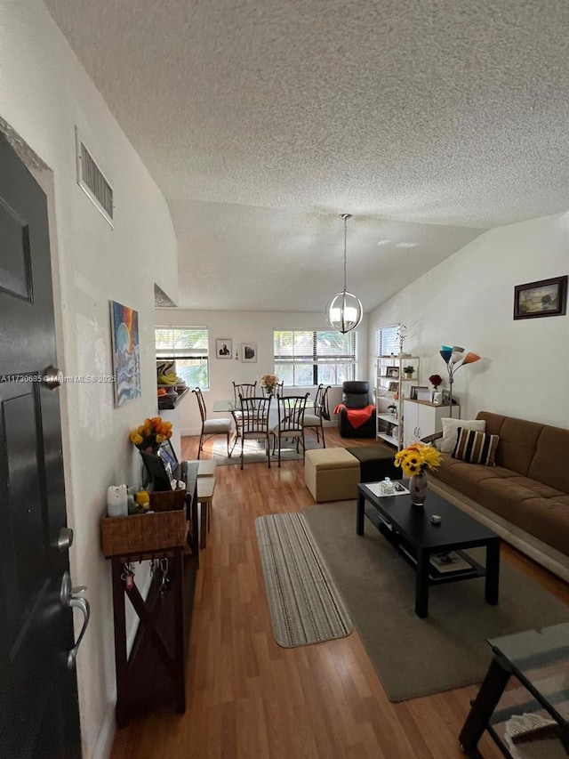 living room featuring vaulted ceiling, hardwood / wood-style floors, and a textured ceiling