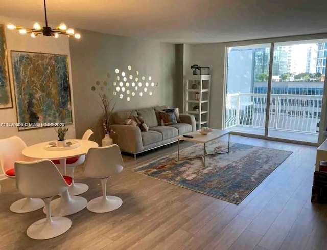 living room with hardwood / wood-style floors, an inviting chandelier, and a wall of windows