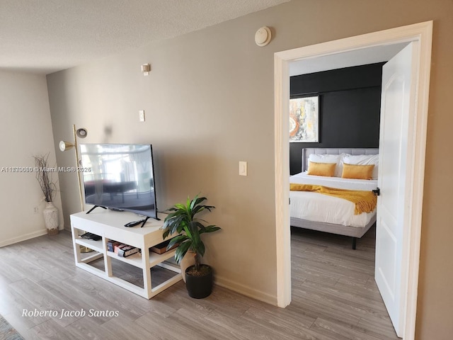 interior space featuring a textured ceiling, wood finished floors, and baseboards