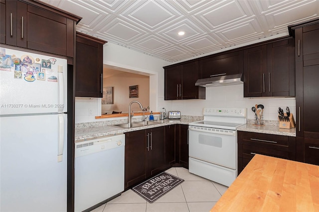 kitchen featuring white appliances, wooden counters, light tile patterned floors, sink, and dark brown cabinets