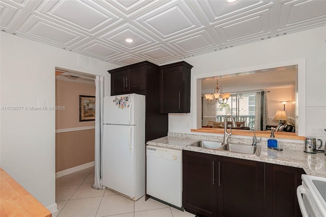 kitchen with sink, light tile patterned floors, light stone countertops, white appliances, and an inviting chandelier