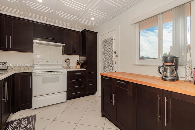 kitchen featuring white electric range oven, dark brown cabinets, light tile patterned flooring, and butcher block countertops