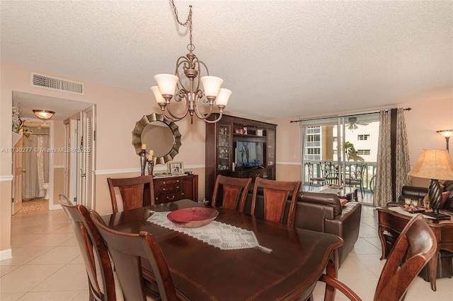 tiled dining area featuring a chandelier and a textured ceiling