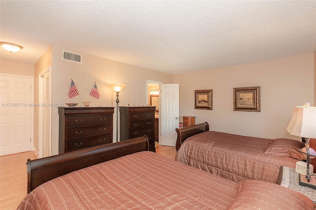 bedroom featuring light wood-type flooring, a textured ceiling, and a closet