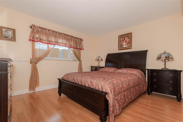 bedroom with light wood-type flooring and a textured ceiling