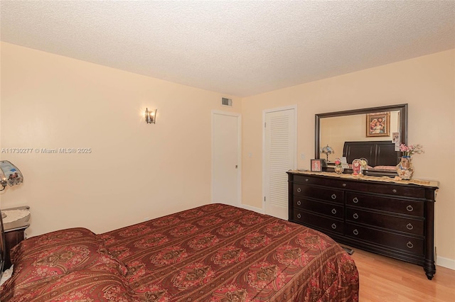 bedroom featuring light wood-type flooring, a textured ceiling, and a closet