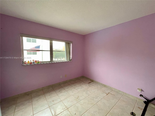 spare room with a textured ceiling and light tile patterned flooring