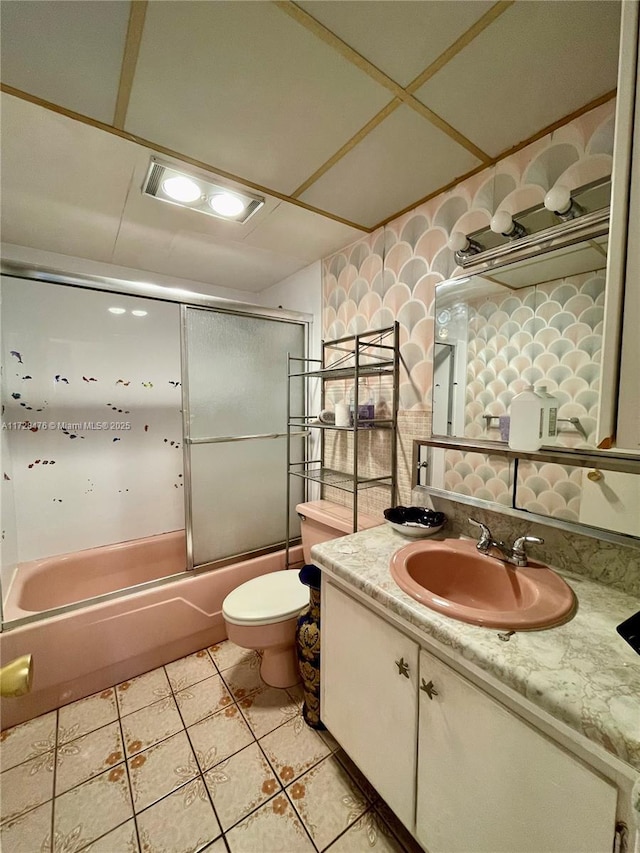 full bath featuring vanity, shower / bath combination with glass door, tile patterned flooring, and toilet