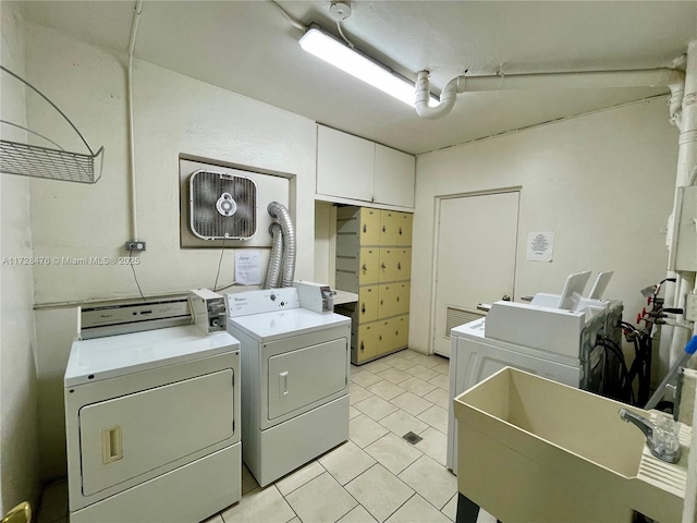 common laundry area featuring light tile patterned floors, a sink, and washing machine and clothes dryer