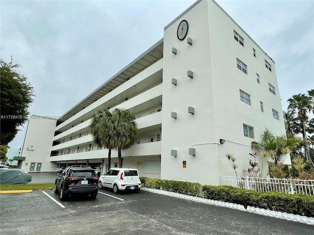 view of building exterior with uncovered parking and fence