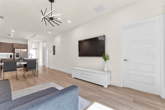 living room with electric panel, light hardwood / wood-style flooring, and an inviting chandelier