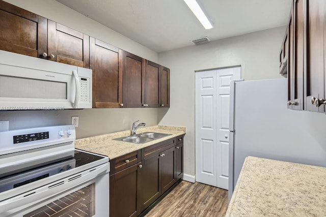 kitchen with sink, white appliances, dark brown cabinets, and dark hardwood / wood-style floors