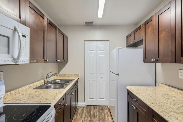 kitchen with dark brown cabinets, sink, dark wood-type flooring, and white appliances