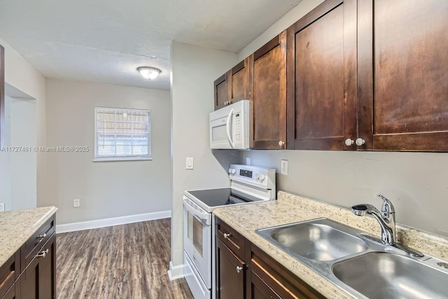 kitchen with dark brown cabinets, sink, dark wood-type flooring, and white appliances