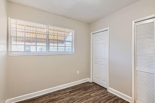 unfurnished bedroom featuring multiple closets and dark hardwood / wood-style floors