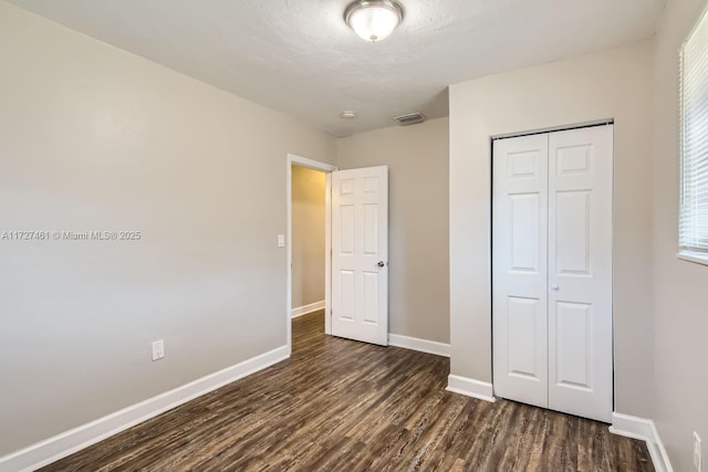 unfurnished bedroom featuring dark hardwood / wood-style flooring and a closet