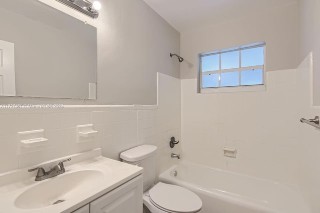 full bathroom featuring vanity, tiled shower / bath combo, toilet, and tile walls