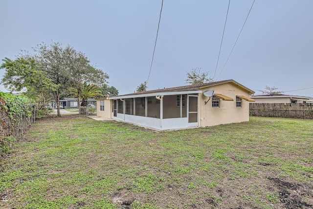 rear view of house with a sunroom and a lawn