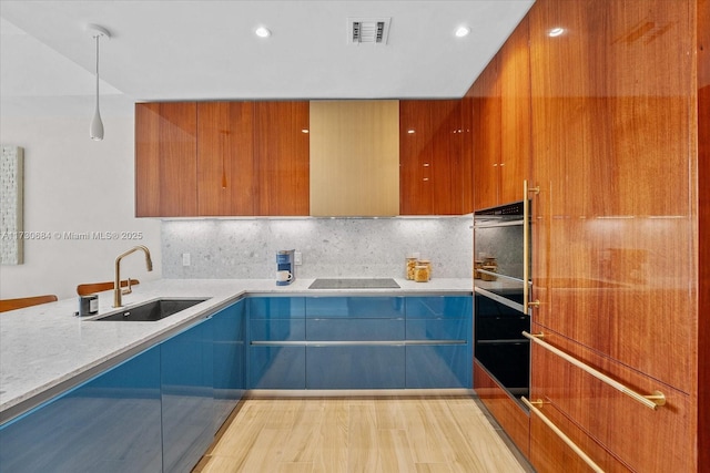 kitchen featuring decorative light fixtures, black electric stovetop, decorative backsplash, sink, and light hardwood / wood-style floors