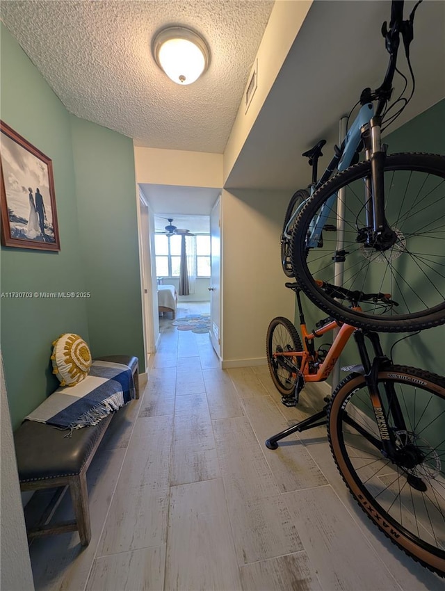 hall featuring light wood-type flooring and a textured ceiling