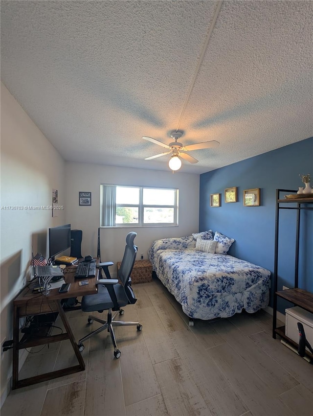 bedroom with hardwood / wood-style flooring, ceiling fan, and a textured ceiling