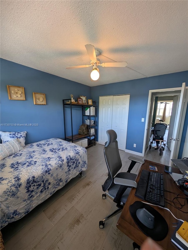 bedroom with ceiling fan, wood-type flooring, a closet, and a textured ceiling