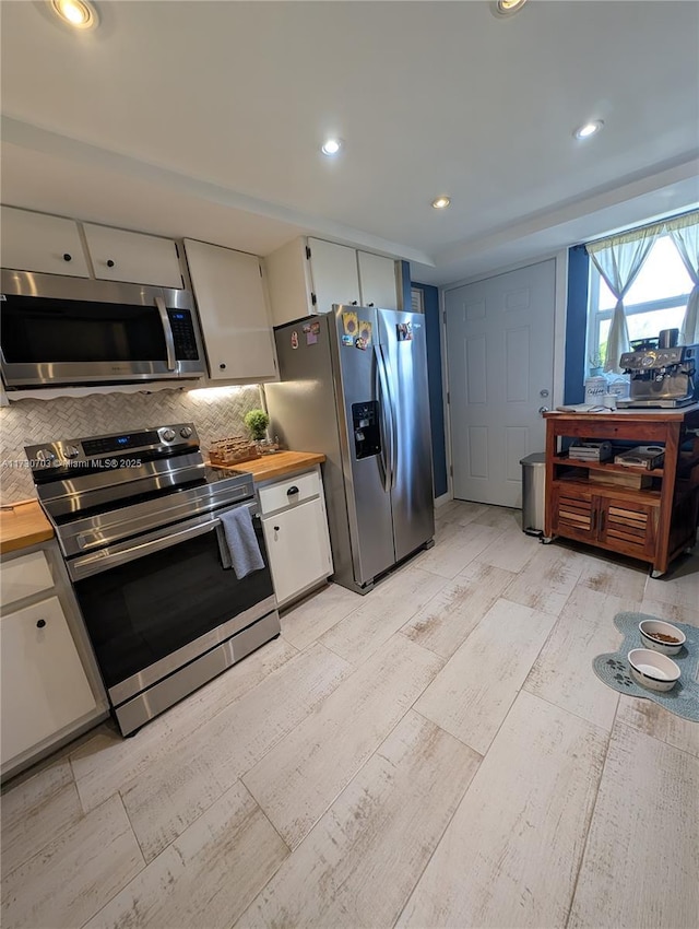 kitchen with white cabinetry, backsplash, wooden counters, and appliances with stainless steel finishes