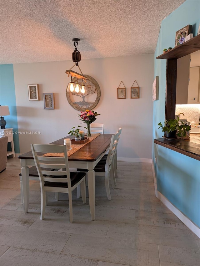 dining space featuring light hardwood / wood-style flooring and a textured ceiling