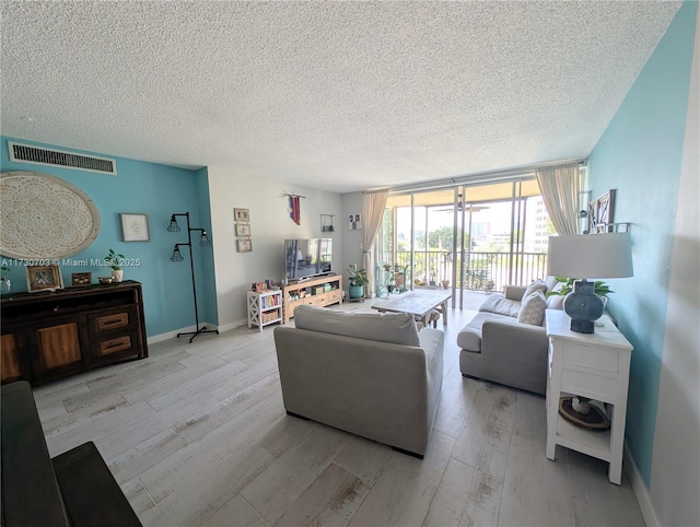 living room with expansive windows, light hardwood / wood-style floors, and a textured ceiling