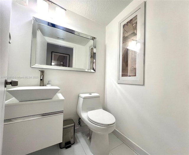 bathroom featuring vanity, toilet, tile patterned floors, and a textured ceiling