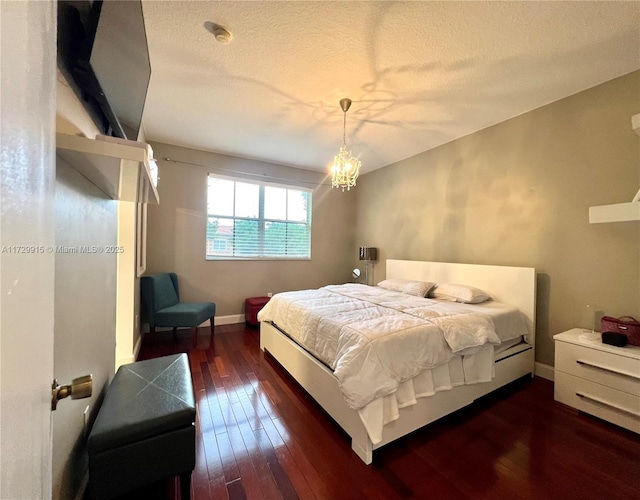 bedroom featuring an inviting chandelier, a textured ceiling, and dark hardwood / wood-style flooring