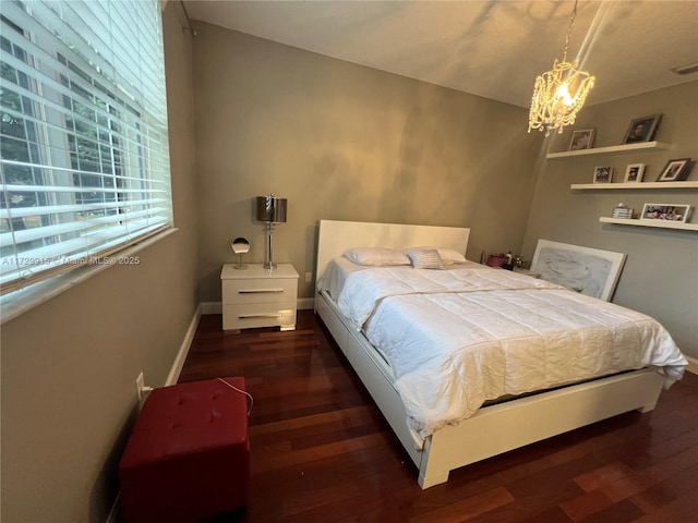 bedroom featuring a notable chandelier and dark wood-type flooring