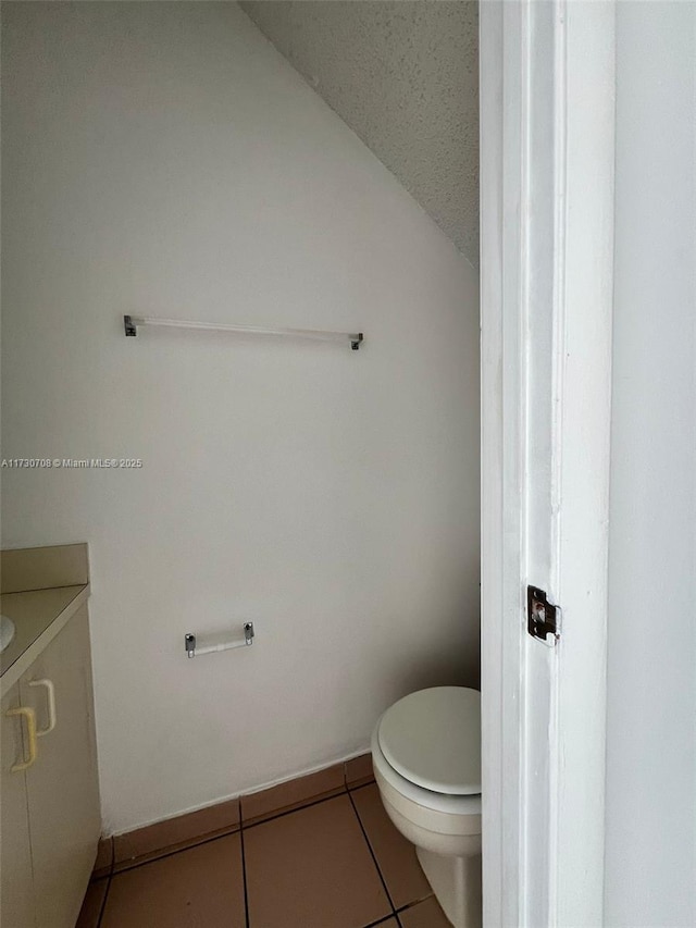 bathroom featuring toilet, tile patterned floors, lofted ceiling, and vanity