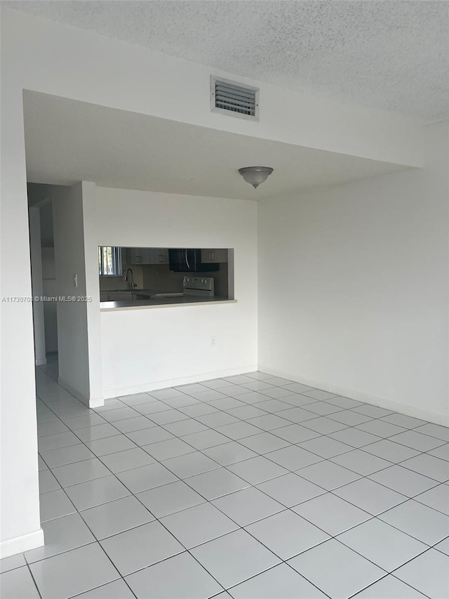 unfurnished living room with a textured ceiling and light tile patterned floors