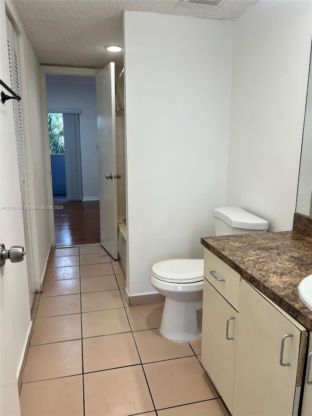 full bathroom with toilet, a textured ceiling, tile patterned flooring, and vanity