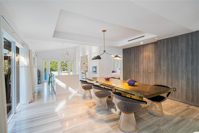 dining room featuring a tray ceiling, wood walls, and french doors