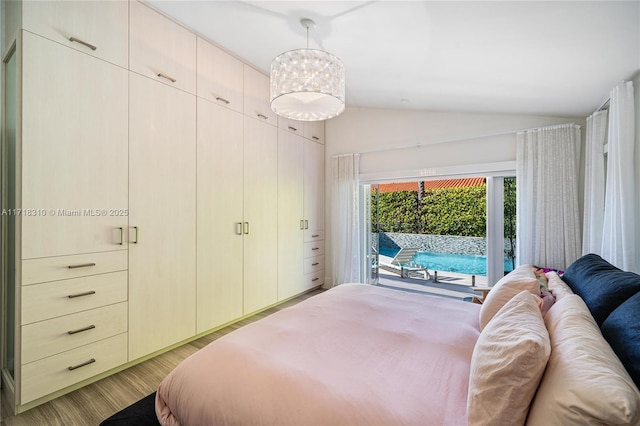 bedroom with light wood-type flooring, access to exterior, a notable chandelier, and vaulted ceiling