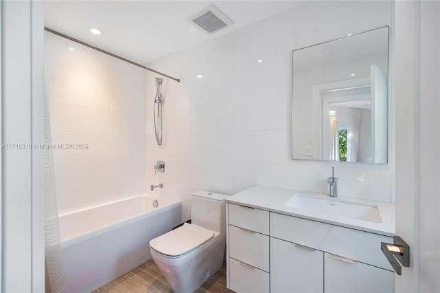 full bathroom featuring toilet, vanity, bathtub / shower combination, and tile walls