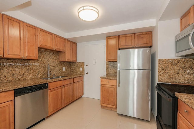 kitchen featuring light stone countertops, stainless steel appliances, sink, backsplash, and light tile patterned floors