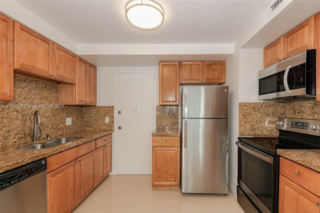 kitchen featuring sink, light stone counters, backsplash, and stainless steel appliances