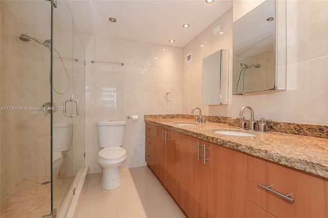 bathroom featuring toilet, tile walls, tile patterned floors, vanity, and a shower with door